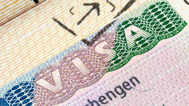 Close-up image of a passport page partially open, displaying a Schengen visa sticker with the European Union emblem.